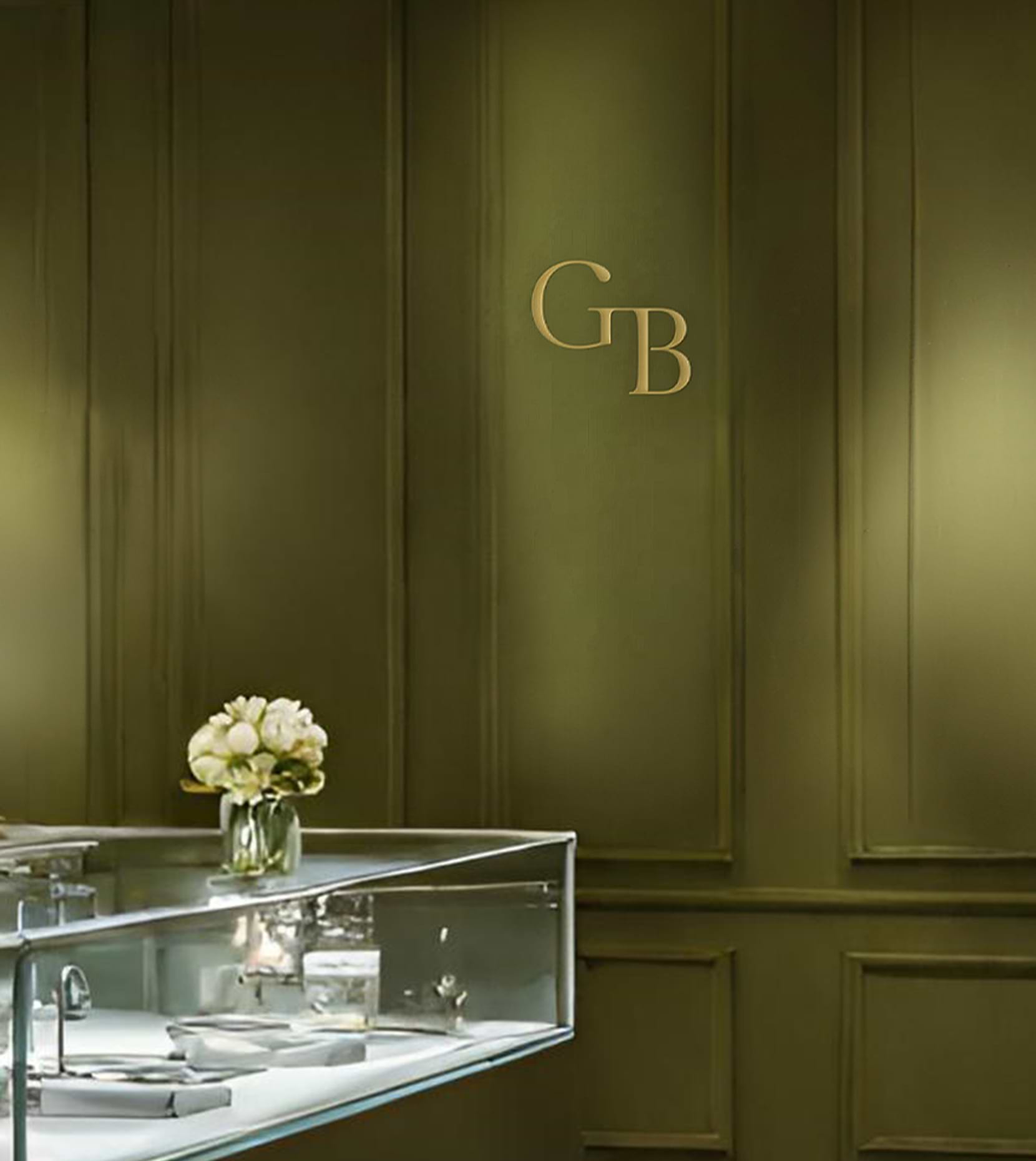 An image of one of our dark green painted showrooms with floral light fixtures and clear display cases is pictured.