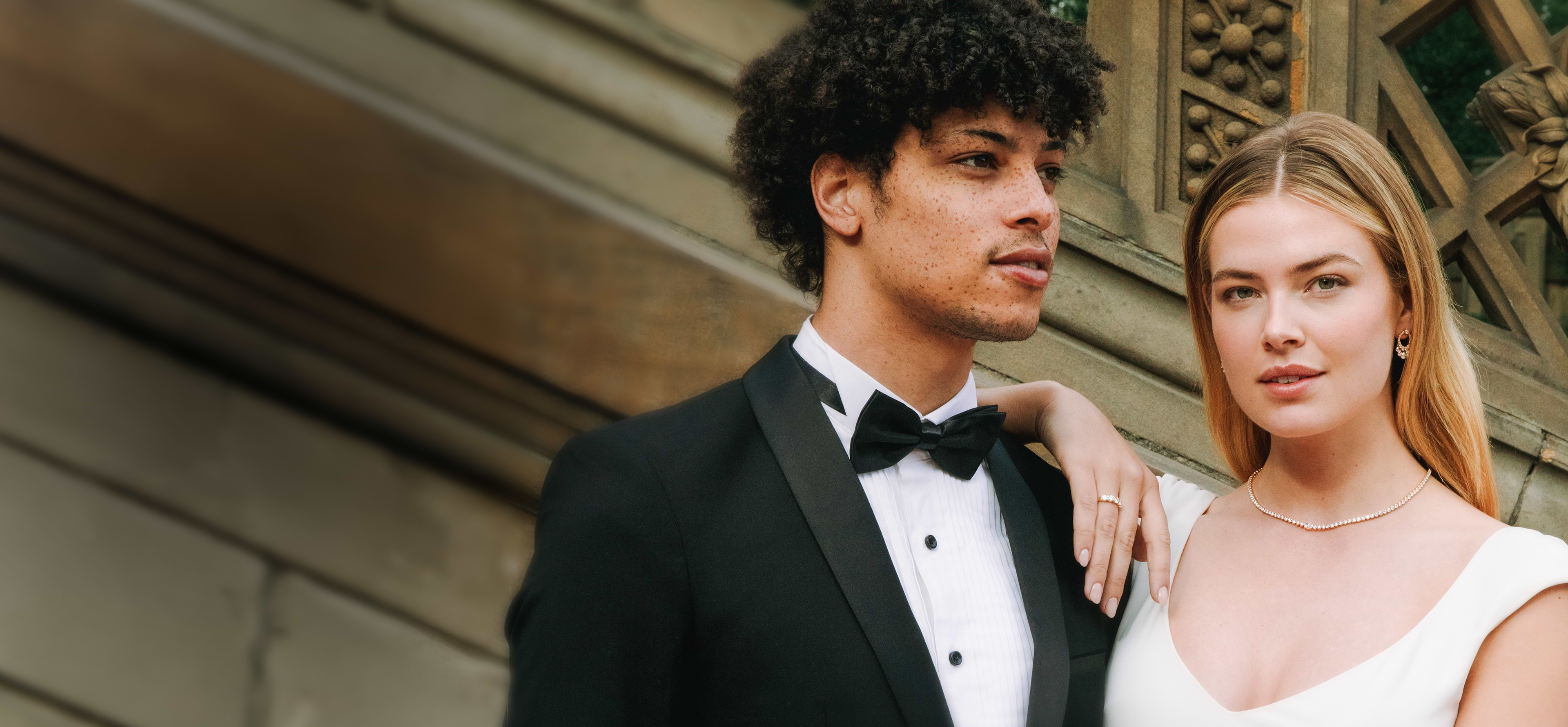 An elegant couple wearing diamond jewelry, with options to shop engagement and fine jewelry.