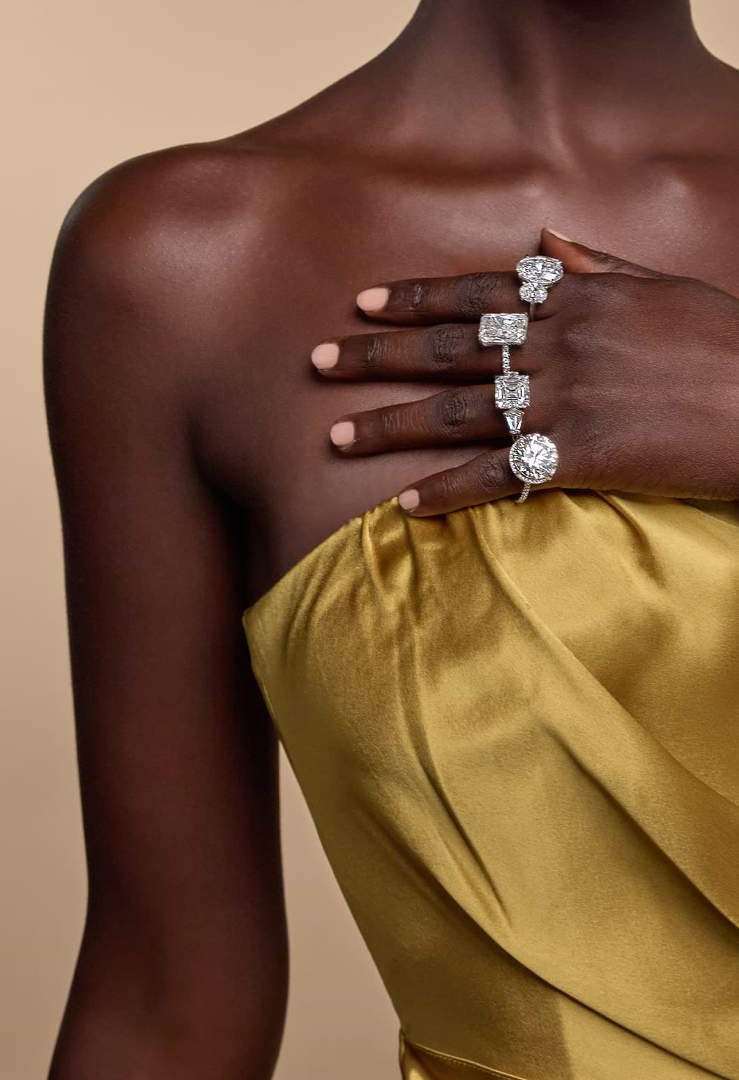 Die Hand eines weiblichen Models liegt sanft auf ihrer Brust und trägt vier Diamant-Verlobungsringe