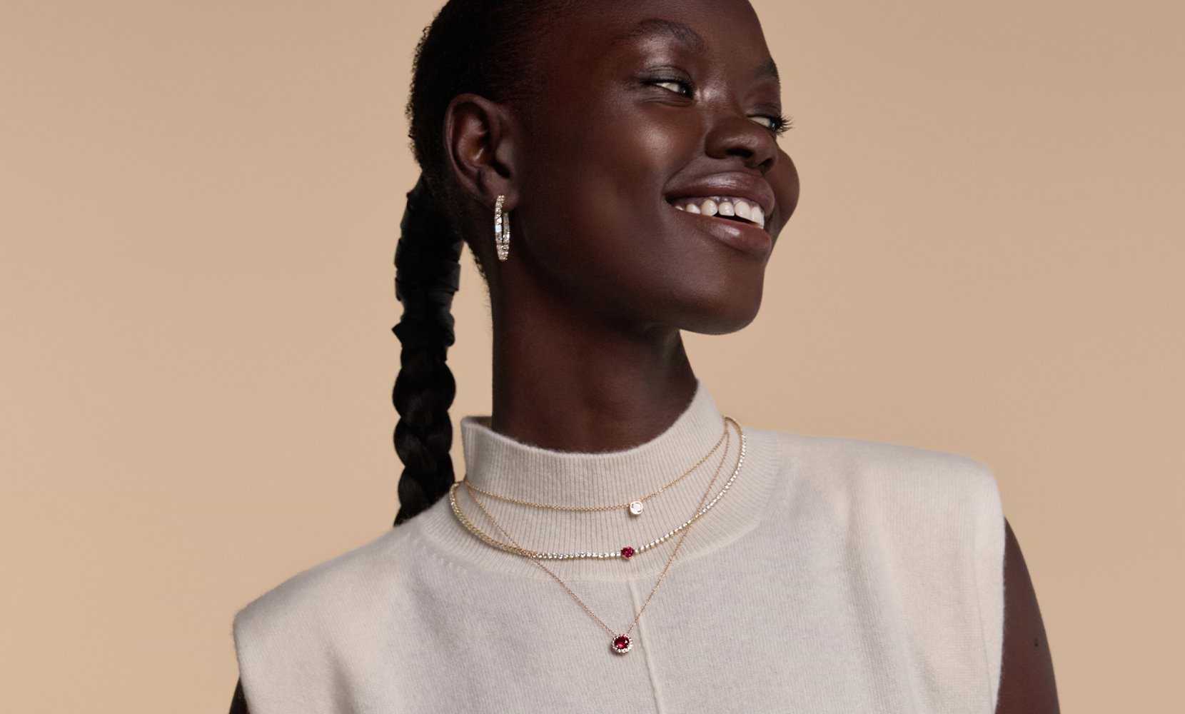 Side profile of a female model wearing three fashion necklaces and diamond hoops