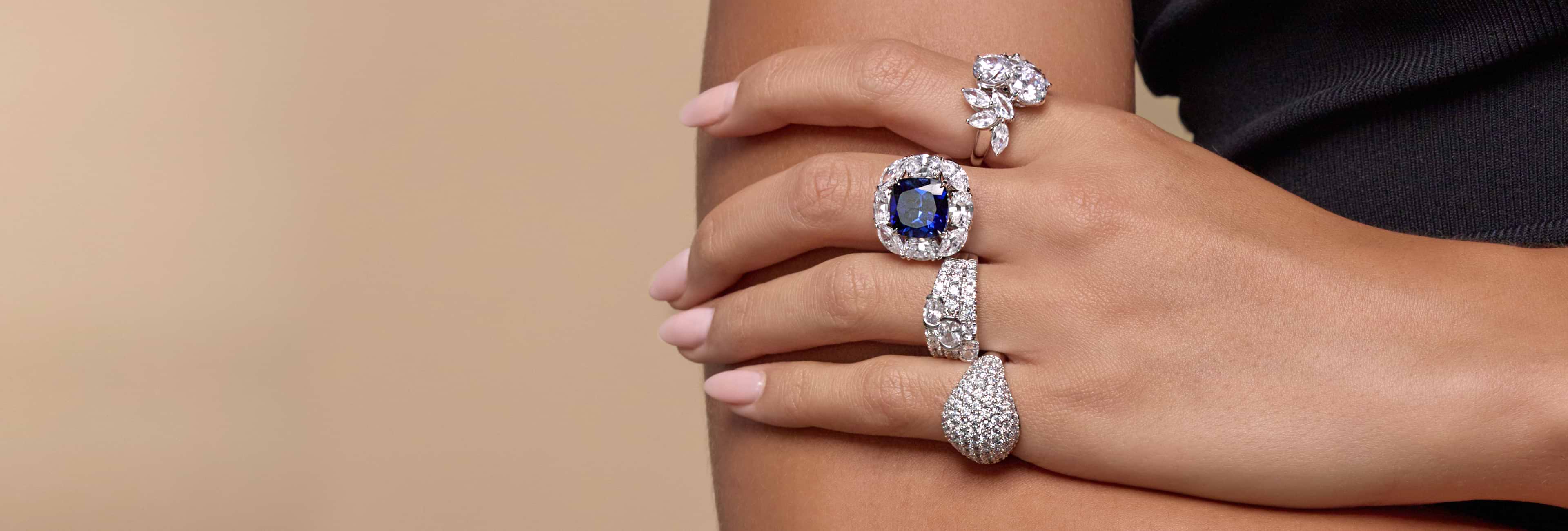 White woman's hand wearing four different fashion rings